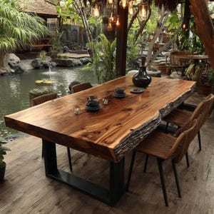 Puede incluir: Una gran mesa de comedor rectangular con un tablero de madera maciza de borde natural, que muestra vetas visibles y textura de corteza en los laterales. La mesa está sostenida por una base de metal negro en forma de U y sillas tejidas.