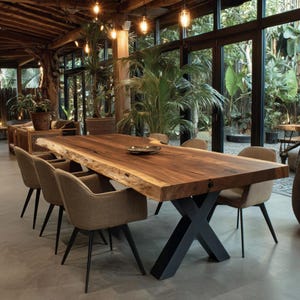 Peut inclure: Une grande table à manger rectangulaire avec un plateau en bois massif à bord naturel et une base en métal noir en forme de X, entourée de six fauteuils rembourrés en tissu marron clair avec des pieds fins en métal noir.