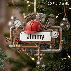 May include: A 2D flat acrylic ornament featuring a wooden plank with the name Jimmy printed in black. The design includes a red hard hat, a metal pipe system with valves, a tape measure, a wrench, and two round pressure gauges with dials.