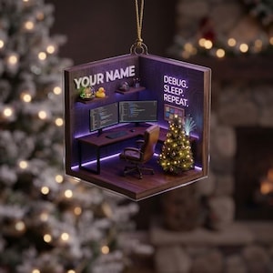 May include: A square, hanging ornament featuring a miniature office scene with a desk, two computer monitors, a brown chair, and a small Christmas tree. The text 'YOUR NAME' and 'DEBUG. SLEEP. REPEAT.' are visible on the dark wood-paneled walls.