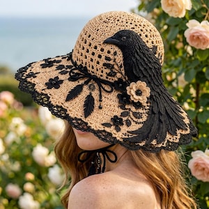 May include: A beige crocheted sun hat featuring a prominent black raven appliqué on the side. The hat is decorated with black lace trim, black feather charms, and small crocheted flowers. A black ribbon tie is attached under the brim.
