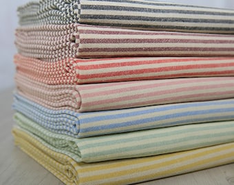May include: A stack of six striped fabric swatches in various colors, including black, red, pink, blue, green, and yellow. The fabric is folded neatly and the stripes are evenly spaced.