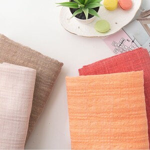 May include: Four fabric swatches in different colors: light pink, brown, orange, and red. The fabric has a textured, woven look.