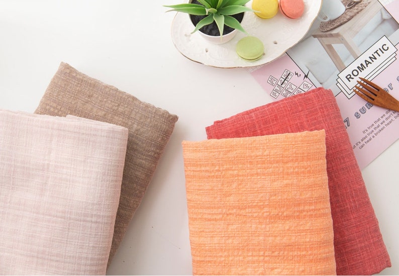 May include: Four fabric swatches in different colors: light pink, brown, orange, and red. The fabric has a textured, woven look.