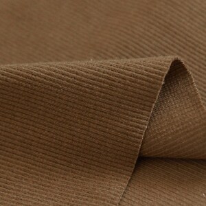 May include: Close-up of brown corduroy fabric with a ribbed texture.