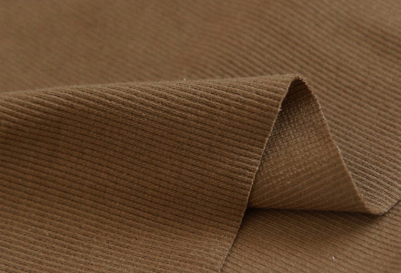 May include: Close-up of brown corduroy fabric with a ribbed texture.
