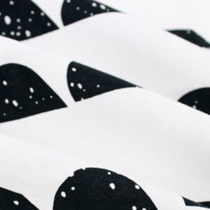 May include: White fabric with a black and white geometric pattern of abstract shapes. The shapes are scattered across the fabric and have a speckled texture.