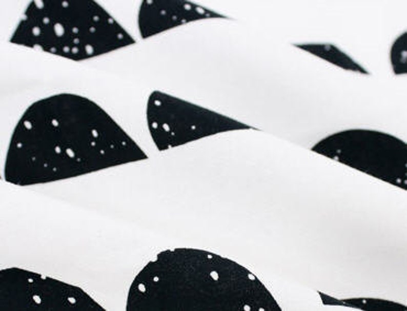 May include: White fabric with a black and white geometric pattern of abstract shapes. The shapes are scattered across the fabric and have a speckled texture.
