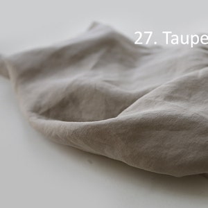 May include: A close-up of a piece of taupe fabric, showing its texture and drape. The fabric is soft and wrinkled, with a subtle sheen. 27. Taupe