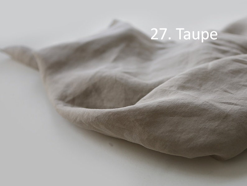 May include: A close-up of a piece of taupe fabric, showing its texture and drape. The fabric is soft and wrinkled, with a subtle sheen. 27. Taupe