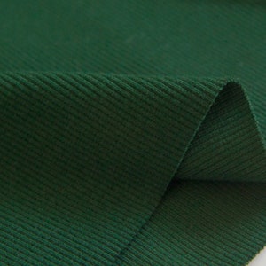 May include: Close-up of a dark green ribbed fabric. The fabric has a soft, textured surface.
