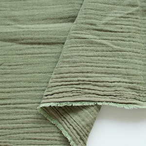 May include: A close-up of a folded piece of green fabric with a textured surface. The fabric has a raw edge and is folded over itself.