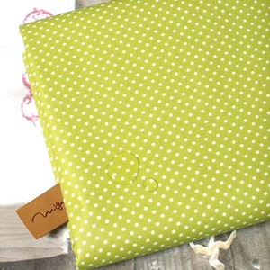 May include: A green fabric with white polka dots. The fabric is waterproof and has water droplets on it.