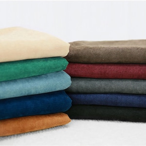 May include: A stack of ten fabric swatches in various colors, including beige, green, blue, red, gray, navy, and brown. The fabric has a corduroy texture.