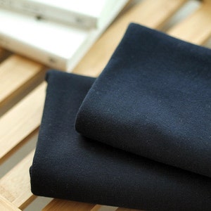 Puede incluir: Dos piezas de tela azul oscuro dobladas sobre una superficie de madera.