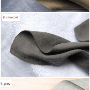 May include: Three fabric swatches in different colors: light khaki, charcoal, and grey. The swatches are folded in a triangular shape and placed on different surfaces.