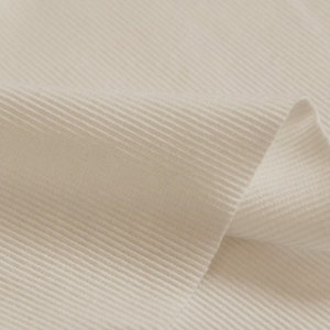 May include: Close-up of a white ribbed fabric with a slight fold. The fabric has a smooth, soft texture.