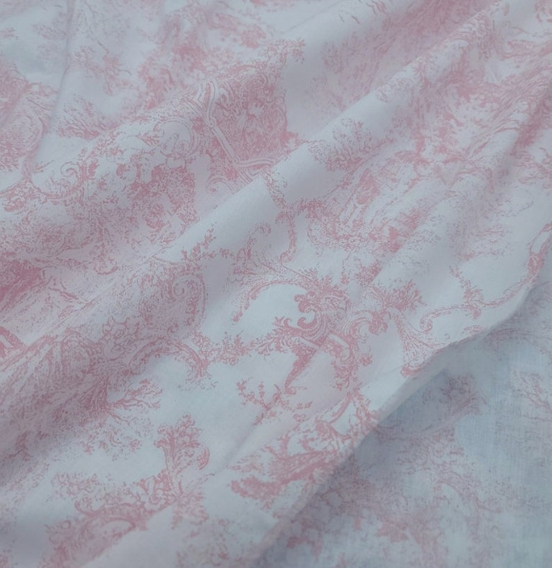 May include: White fabric with a pink floral pattern. The fabric has a subtle sheen and a soft texture.