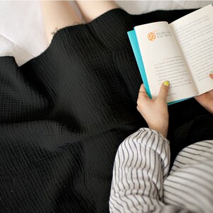 Op de afbeelding: Een persoon draagt een zwarte rok en een gestreept shirt en leest een boek met een blauwe kaft. Het boek heeft Koreaanse tekst op de kaft.