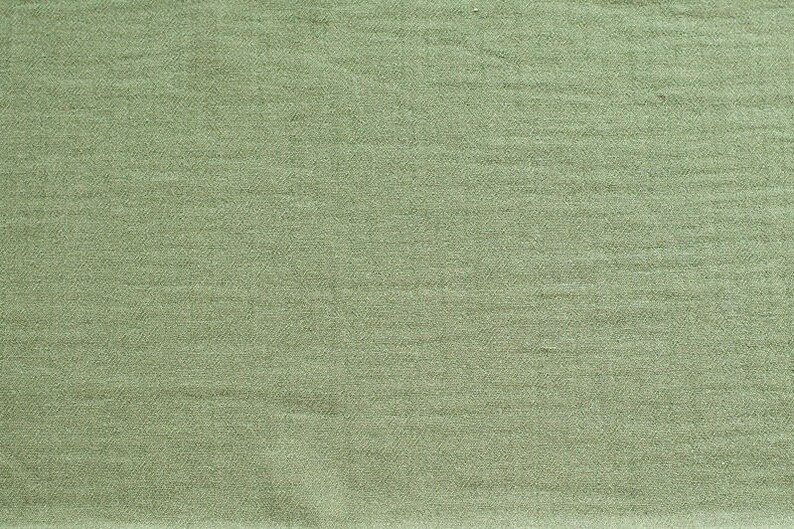 May include: A close-up of a smooth, green fabric with a subtle texture. The fabric has a slightly sheen finish.