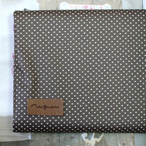 May include: Brown fabric with a white polka dot pattern. The fabric has a brown leather label with the text "nigma" on it.