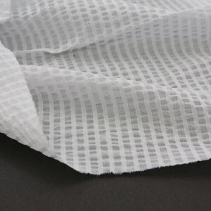 May include: White cotton fabric with a grid pattern. The fabric is sheer and has a slightly textured surface.