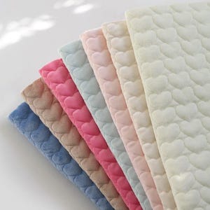 Può includere: Un set di sei campioni di tessuto in vari colori, ognuno con un motivo a cuore trapuntato. I colori sono blu, beige, rosa, azzurro, rosa chiaro e bianco.