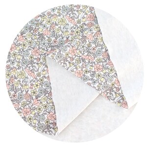 May include: A white fabric with a floral pattern in shades of pink, yellow, and grey. The fabric is folded in half, showing the white side on the bottom.