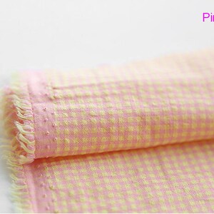 Pu&ograve; includere: Tessuto gingham rosa e giallo con un bordo sfrangiato. Il tessuto &egrave; piegato a met&agrave; e il testo "Pink Yellow" &egrave; visibile in alto a destra.