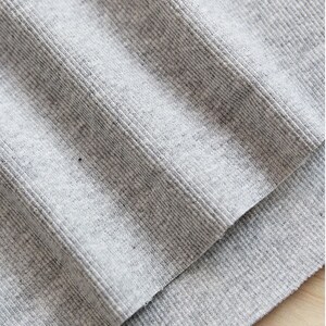 May include: Close-up of a gray ribbed fabric. The fabric is folded over itself, showing the texture of the material.