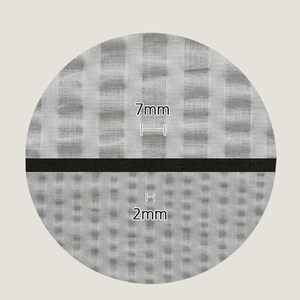 May include: Close-up of a gray fabric with two different weave patterns. The top pattern has larger squares and the bottom pattern has smaller squares. The top pattern is labeled "7mm" and the bottom pattern is labeled "2mm".