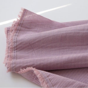 May include: Pink and purple striped fabric with a fringed edge.