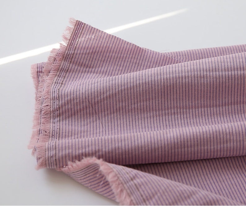 May include: Pink and purple striped fabric with a fringed edge.