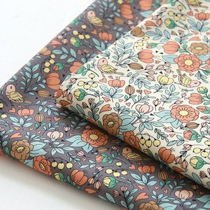 May include: Two pieces of fabric with a floral pattern. One fabric is a light beige with a light blue, pink, and orange floral pattern. The other fabric is a dark gray with a light blue, pink, and orange floral pattern.