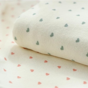 May include: Two white fabric swatches with different colored heart patterns. The top swatch has a green heart pattern and the bottom swatch has a pink heart pattern.