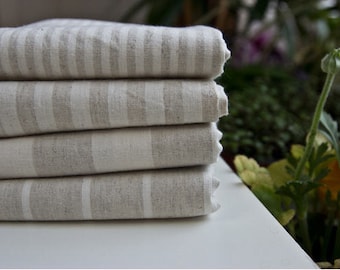May include: A stack of four linen towels with white and gray stripes. The towels are folded neatly and are made of a soft, natural fabric.