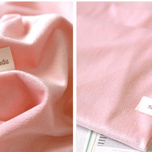 May include: Soft pink fabric with a velvety texture, possibly a blanket or cloth. The fabric is folded and has a small tag that reads "natural style handmade". The overall aesthetic is delicate and gentle.