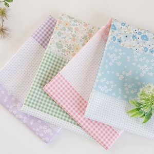 Puede incluir: Cuatro cuadrados de tela con diferentes patrones. El cuadrado superior es una tela azul claro con un patrón floral blanco. El segundo cuadrado es un patrón de cuadros verdes y blancos. El tercer cuadrado es un patrón de cuadros rosas y blancos. El cuadrado inferior es una tela de color morado claro con un patrón floral blanco.