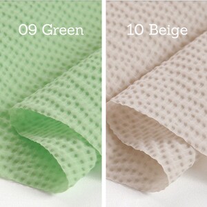 May include: Two pieces of textured fabric, one light green and one beige. The light green fabric is labeled "09 Green" and the beige fabric is labeled "10 Beige". The fabric has a dotted pattern.