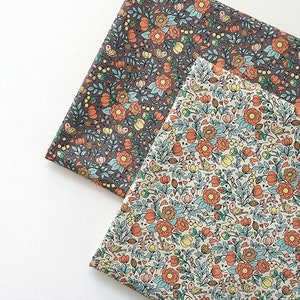 May include: Two fabric squares with a floral pattern. One square is a dark gray background with orange, yellow, and blue flowers. The other square is a light cream background with orange, yellow, and blue flowers.