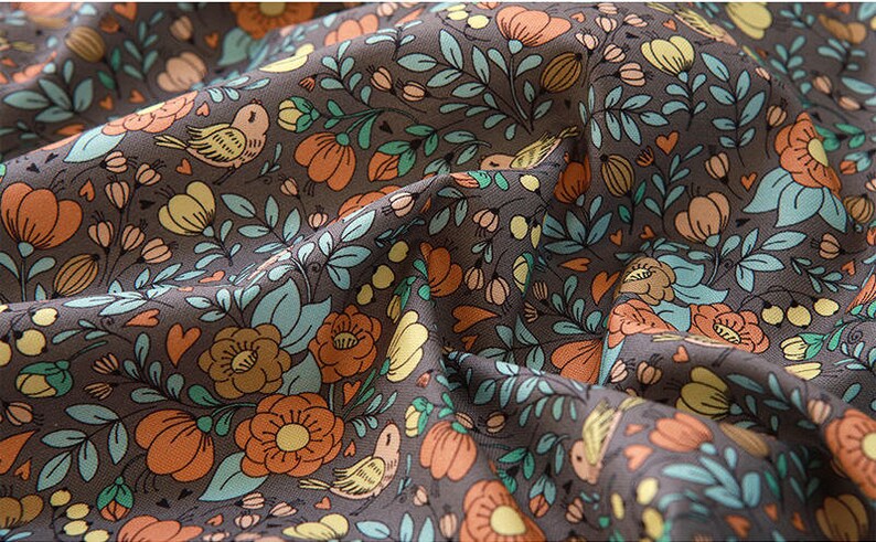May include: A brown fabric with a repeating pattern of orange flowers, green leaves, and small birds. The fabric has a vintage feel and would be perfect for crafting projects.