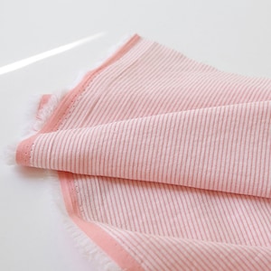 May include: Pink and white striped fabric with a pink border. The fabric has a soft, textured feel.