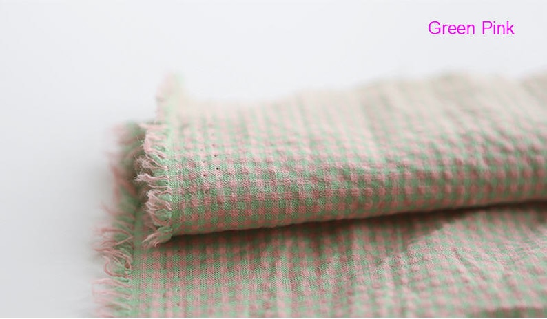 Pu&ograve; includere: Tessuto a quadri verde e rosa con un bordo sfrangiato. Il tessuto &egrave; piegato a met&agrave;.