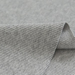 May include: Close-up of a gray ribbed fabric. The fabric is soft and has a subtle texture.