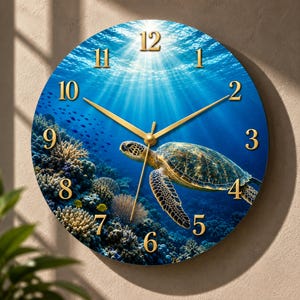 May include: A round wall clock featuring an underwater scene with a sea turtle swimming near a coral reef. The clock face displays a deep blue ocean background with sunlight filtering from above, gold-colored numerals, and thin gold clock hands.