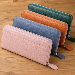 Peut inclure: Quatre portefeuilles rectangulaires à fermeture éclair avec une texture grainée, disposés en rangée diagonale. Les portefeuilles sont de couleur rose clair, bleu poussiéreux, orange brûlé et vert forêt foncé, avec une tirette assortie.