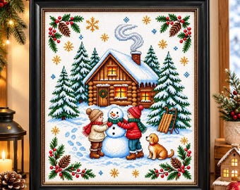 May include: A framed cross-stitch embroidery depicting a winter scene with a log cabin, two children building a snowman, a golden dog, and pine trees. The design is bordered by holly leaves, red berries, and pinecones on a white fabric background.