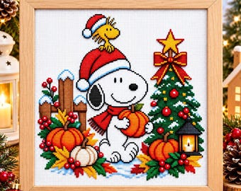 May include: A framed cross-stitch embroidery featuring Snoopy wearing a red Santa hat and scarf, holding an orange pumpkin. Woodstock sits on Snoopy's head. A decorated Christmas tree, autumn leaves, red berries, and a lantern are included.