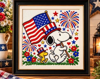 May include: A framed diamond painting featuring Snoopy and Woodstock celebrating with an American flag, a patriotic top hat, fireworks, and red, white, and blue flowers. The design includes scattered stars and hearts on a white grid background.