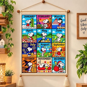 May include: A wall hanging featuring a cross-stitch style calendar with twelve squares, each depicting Snoopy in seasonal scenes for every month of the year. The design includes text labels for January through December, with colorful illustrations of the character.